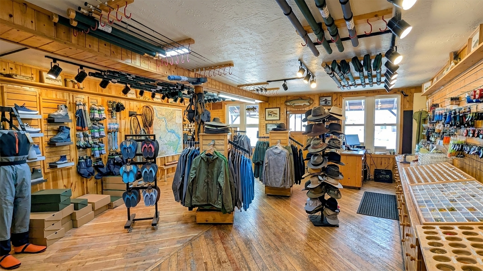 Interior of a fly fishing shop with a wall of rods and bins of flies as a staffer helps an angler