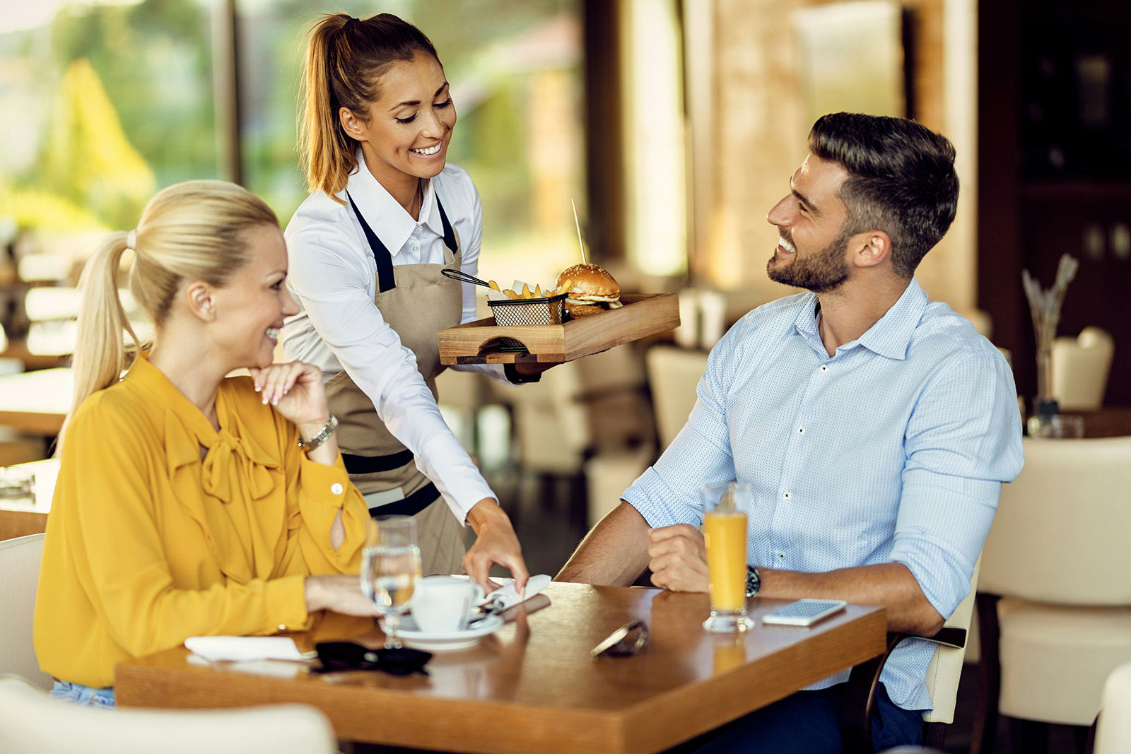 Server taking an order tableside in a warm, busy full-service restaurant