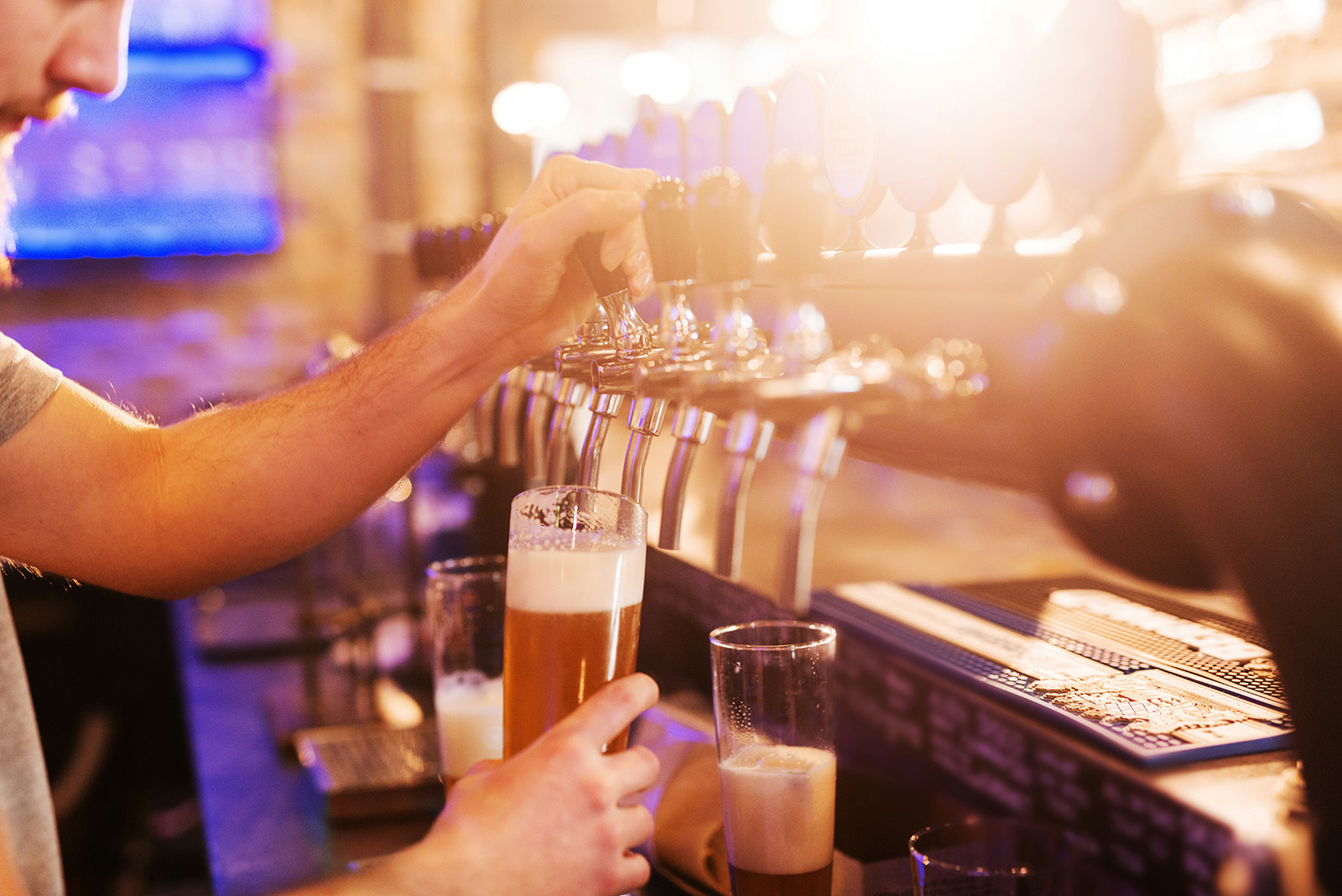 Bartender pouring a drink at a lively bar or brewery taproom