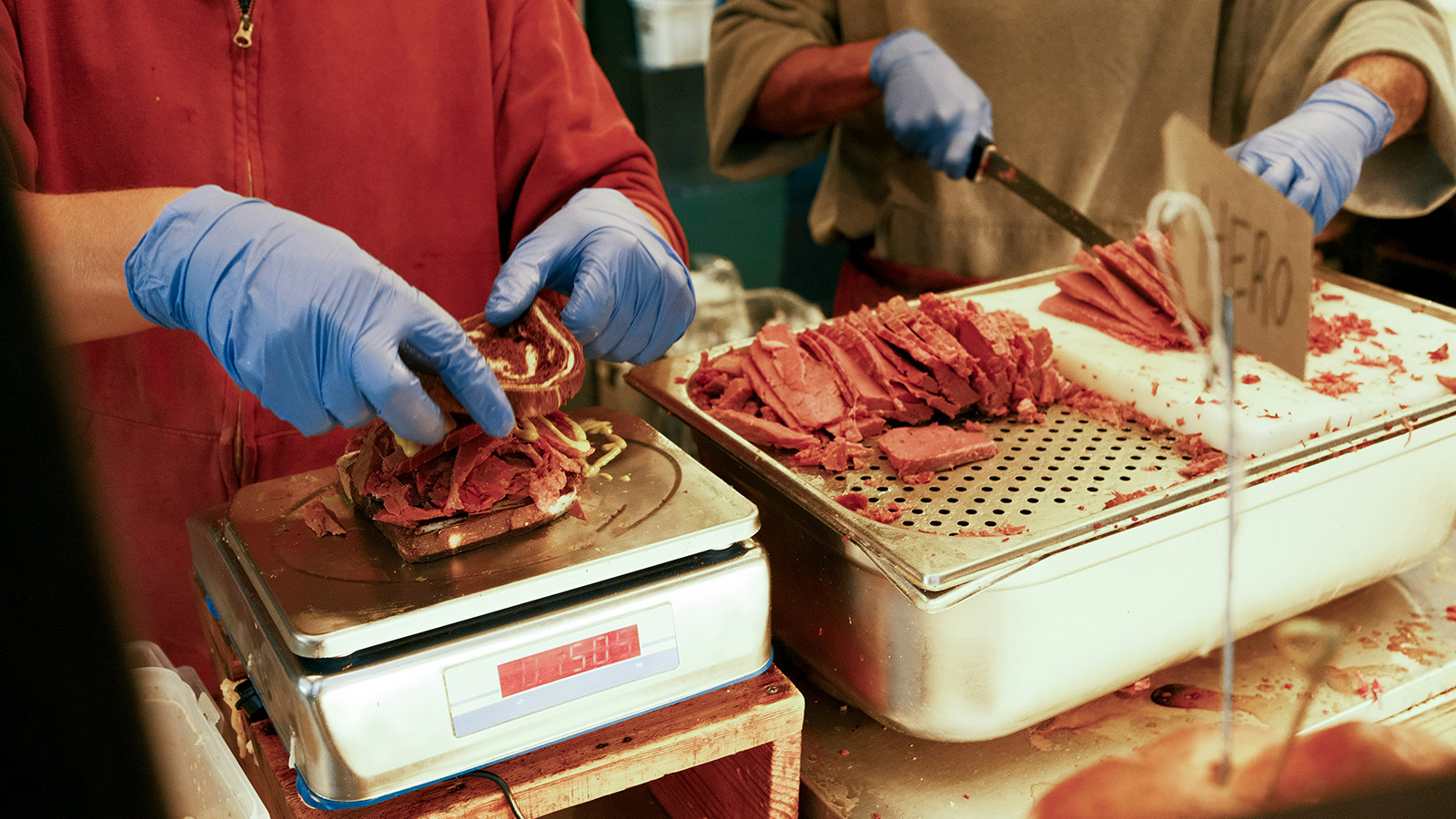Staff serving customers at a busy deli counter with prepared foods on display