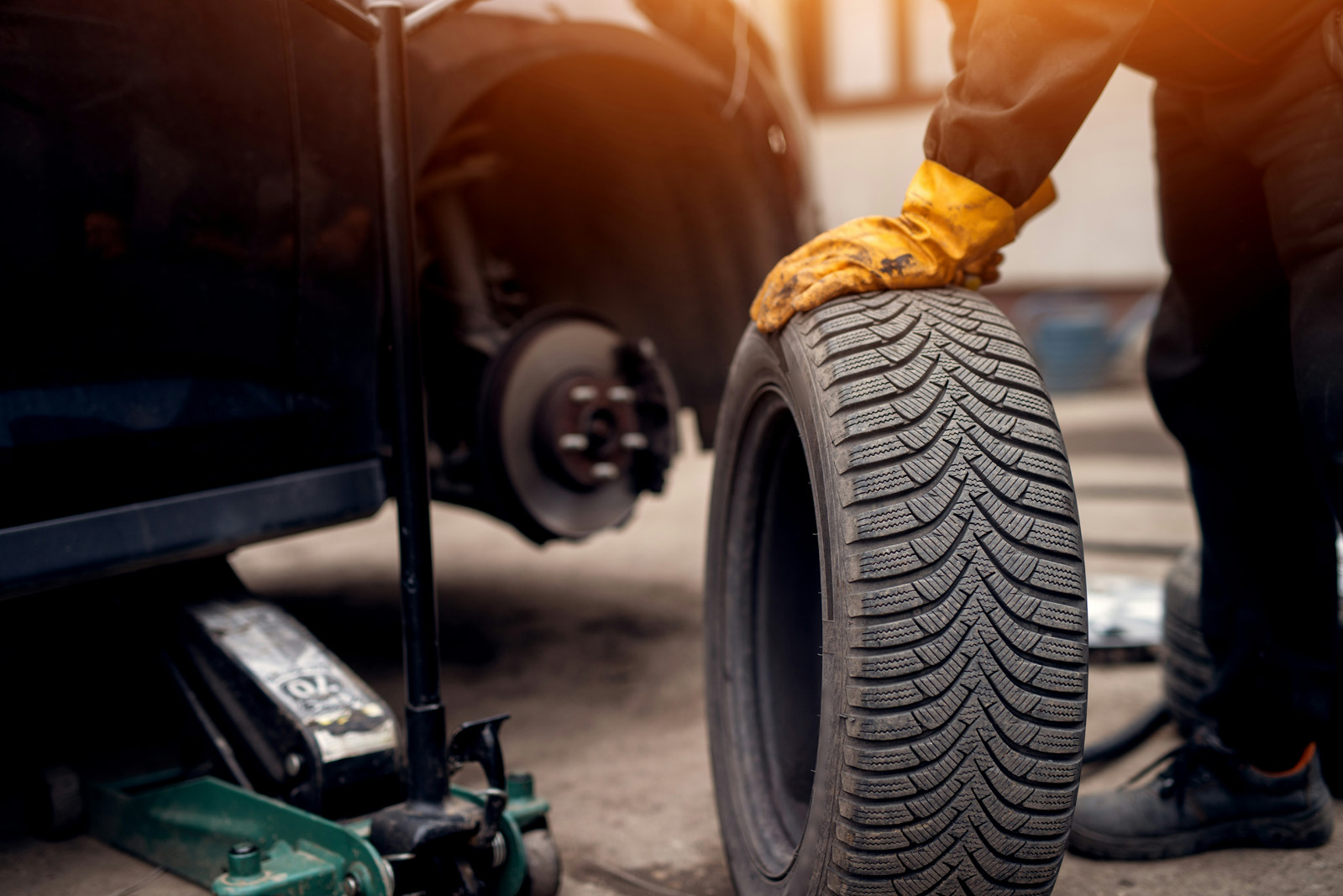 Clean, modern service bay or tire showroom — technician with a vehicle on a lift; warm, professional light