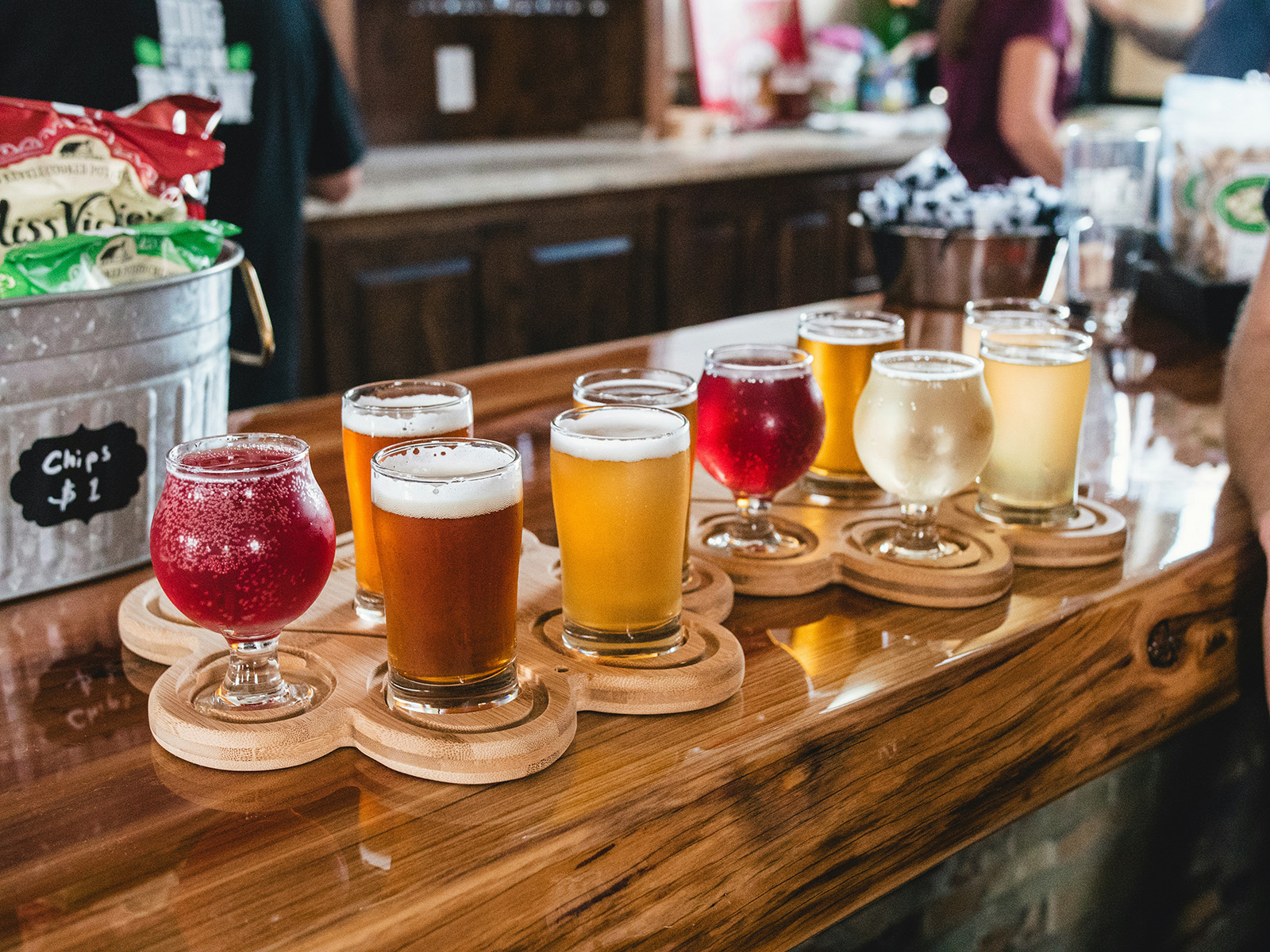 A tasting flight and branded glassware on a taproom bar; warm, craft-beer atmosphere