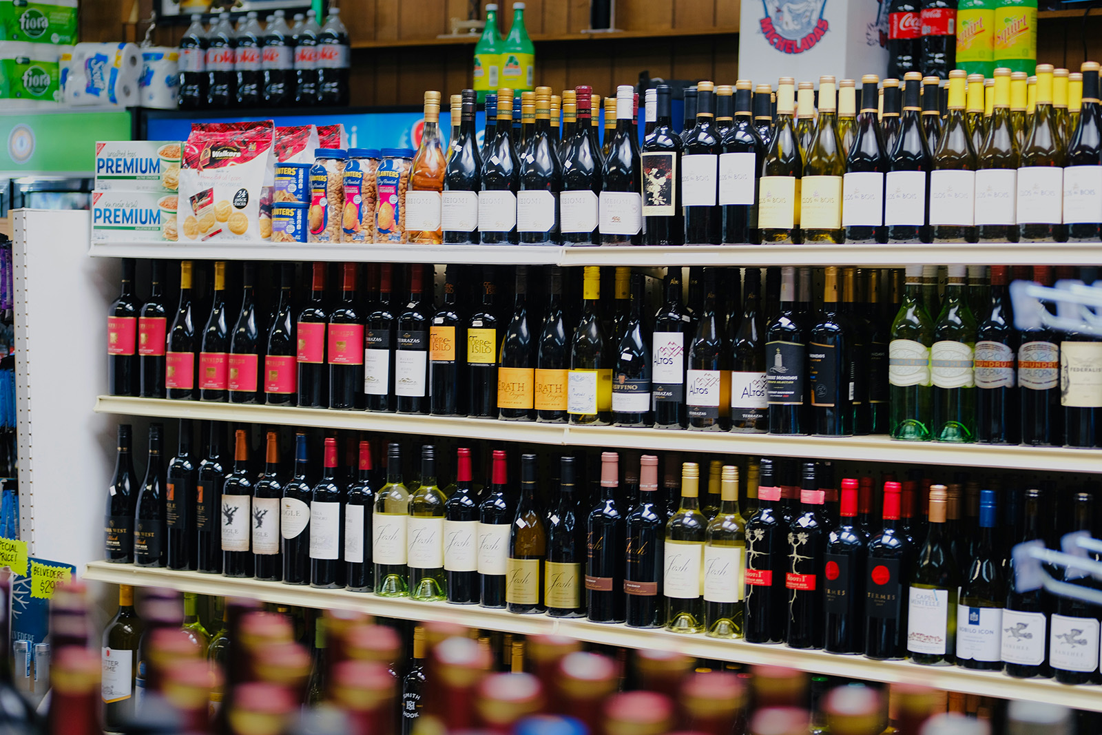 Well-organized wine-and-spirits wall, or a clerk doing a tablet-based inventory count among the shelves