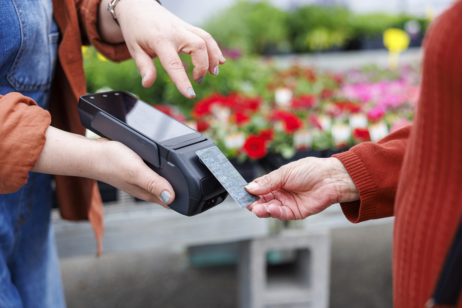 Staff taking a mobile payment at a curbside pickup or outdoor market; bright and candid