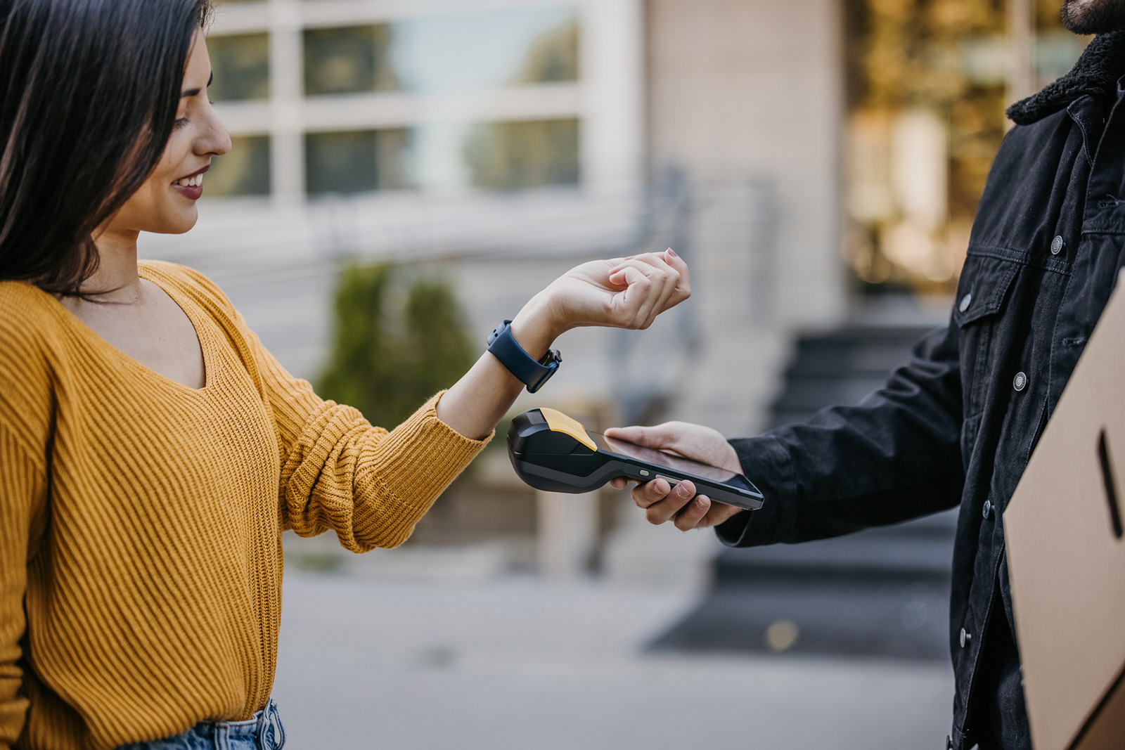 A close-up of a customer tapping a card or phone onto a staff member’s phone or handheld; modern and mobile