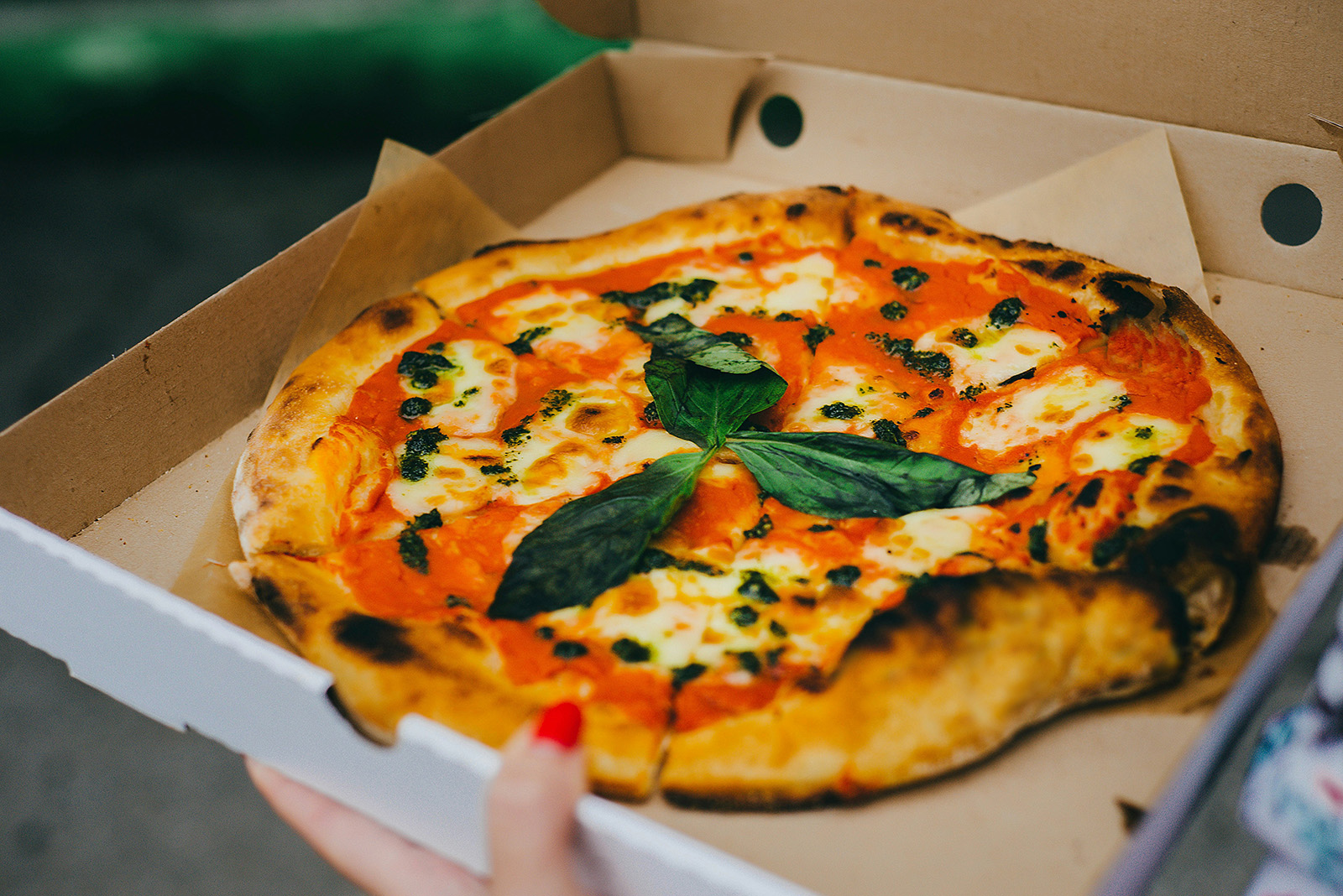 A pizza delivery driver heading out with a stack of boxed pizzas