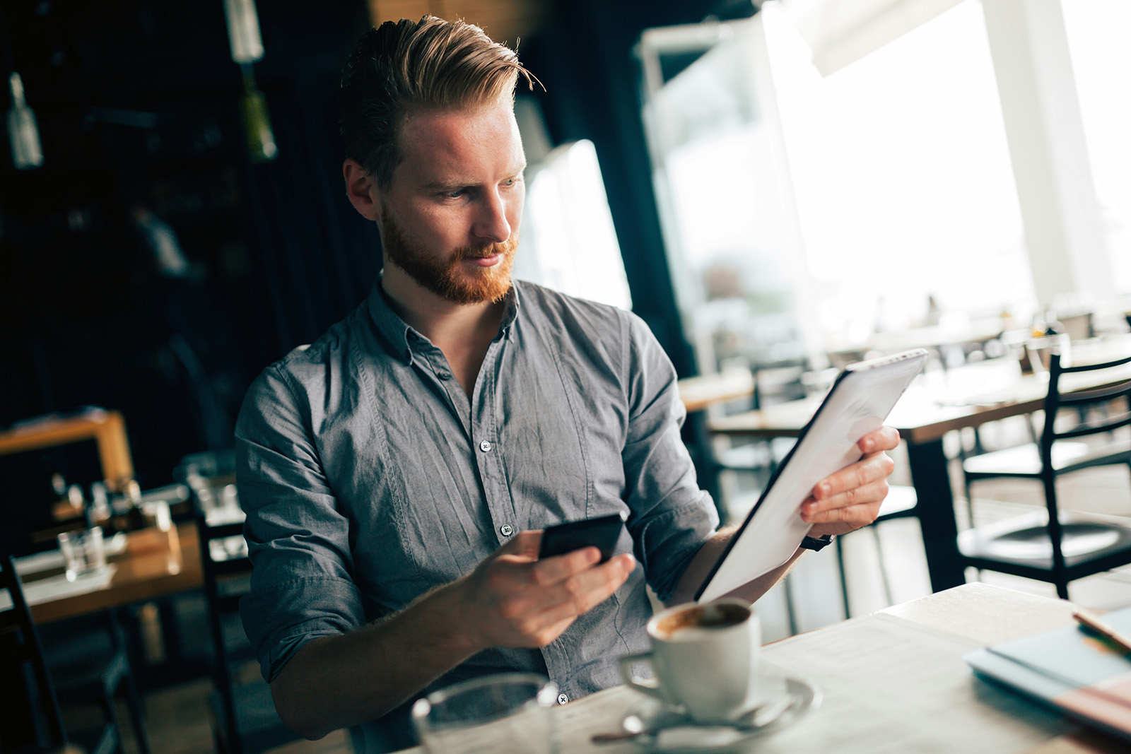 A business owner checking a live sales dashboard on a phone away from the store; confident and in control
