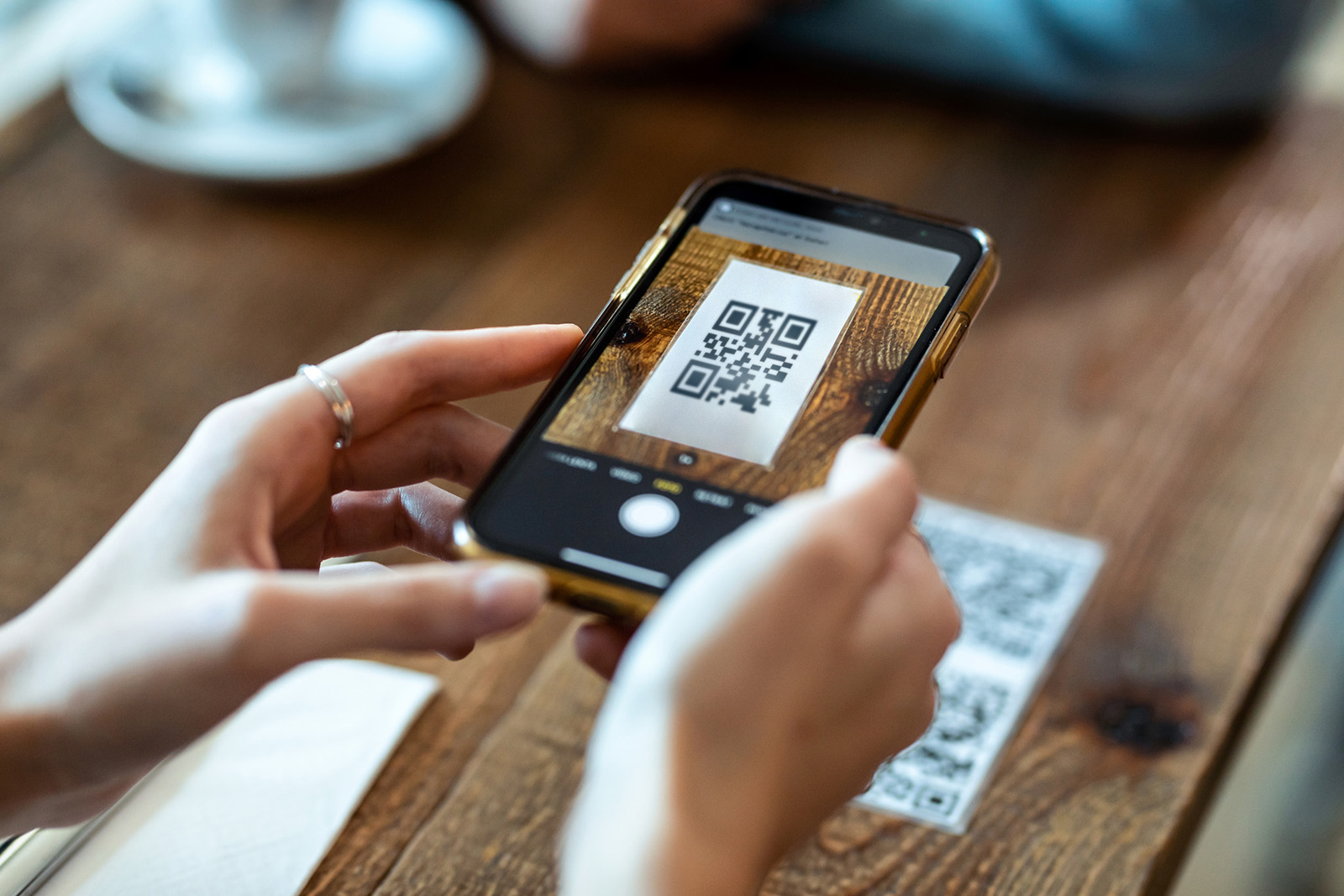 A diner scanning a QR code at the table to pay from their phone; warm restaurant setting