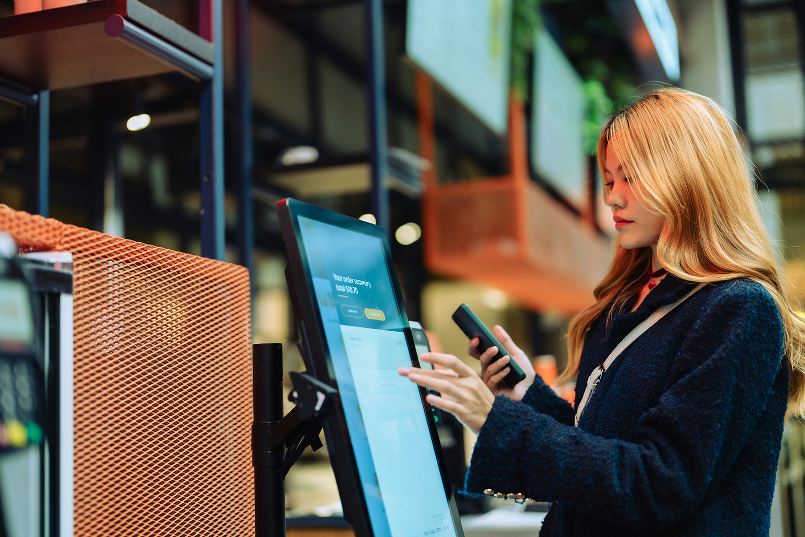 A guest tapping through a self-order kiosk in a bright fast-casual space; modern, frictionless