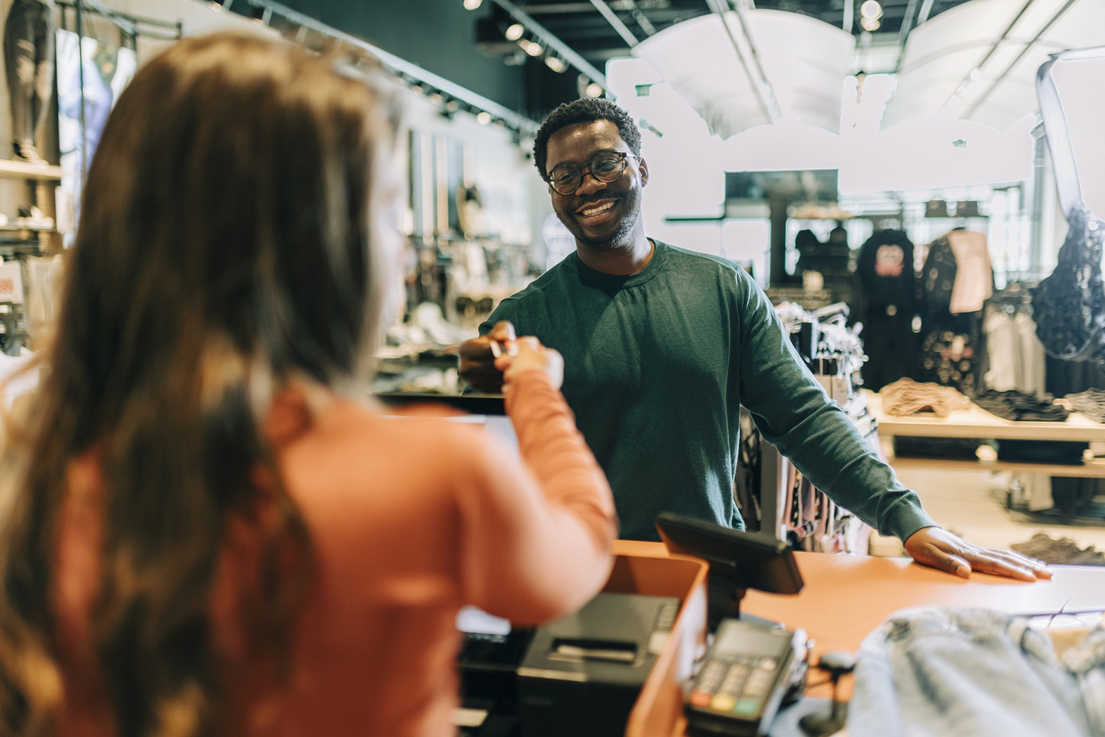Stylish modern shop; an associate ringing up a happy customer on an all-in-one register with a customer-fac…