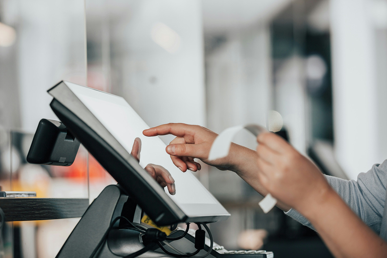 A specialist installing and configuring a POS station and training staff at the counter