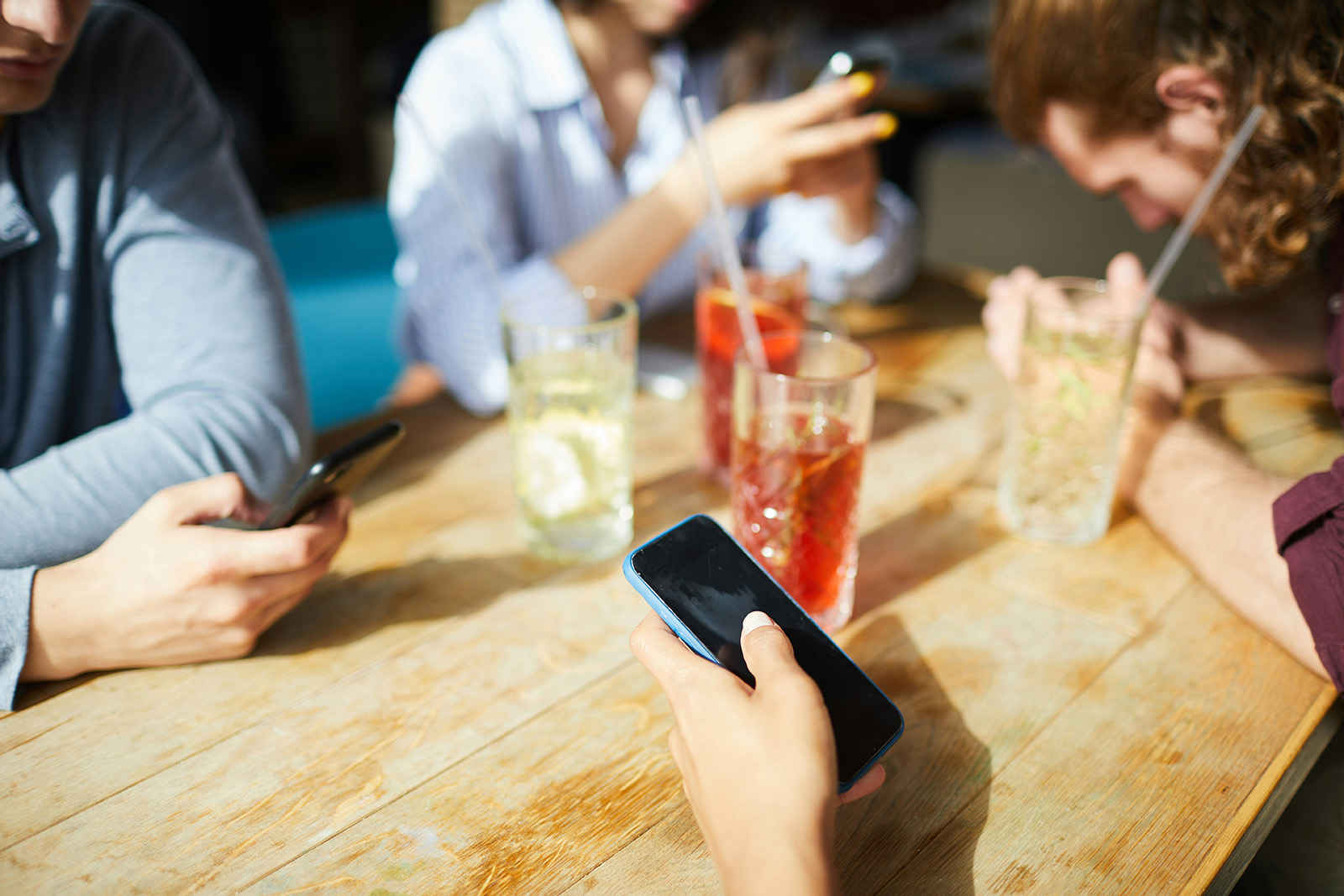 Bar guest placing a drink order on a smartphone at a busy table